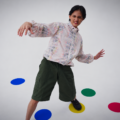 Model mengenakan Foldable Twister Commute Jacket dan celana pendek hijau dengan titik warna di lantai studio