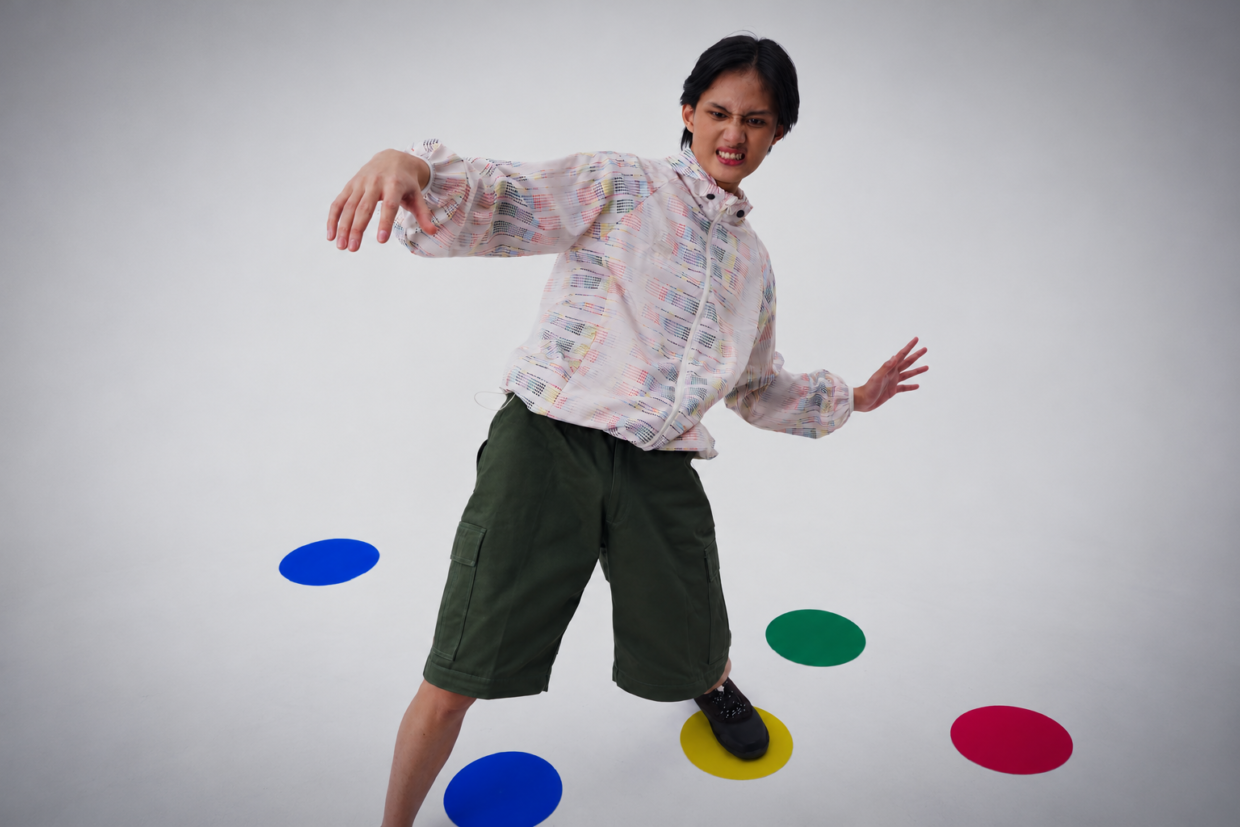 Model mengenakan Foldable Twister Commute Jacket dan celana pendek hijau dengan titik warna di lantai studio