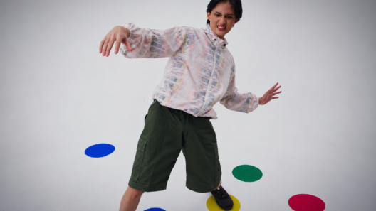Model mengenakan Foldable Twister Commute Jacket dan celana pendek hijau dengan titik warna di lantai studio